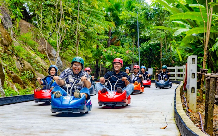 Friends enjoying the Hanuman Luge ride through a lush green forest.