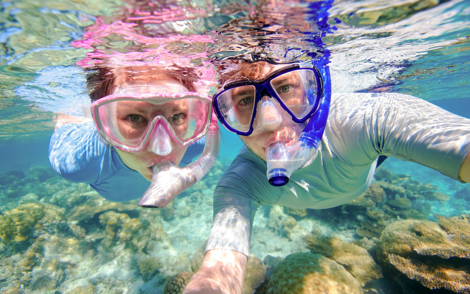 Couple snorkeling near coral reefs in clear waters, Oahu, Hawaii.
