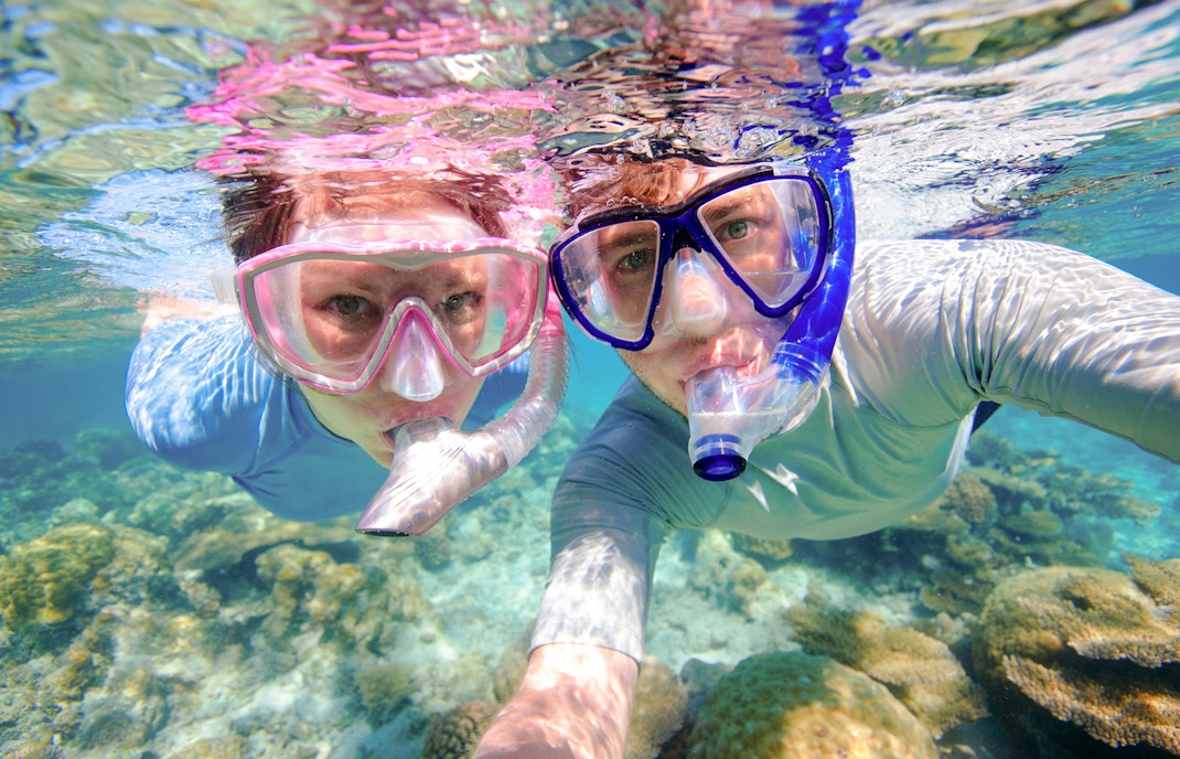 Couple snorkeling near coral reefs in clear waters, Oahu, Hawaii.