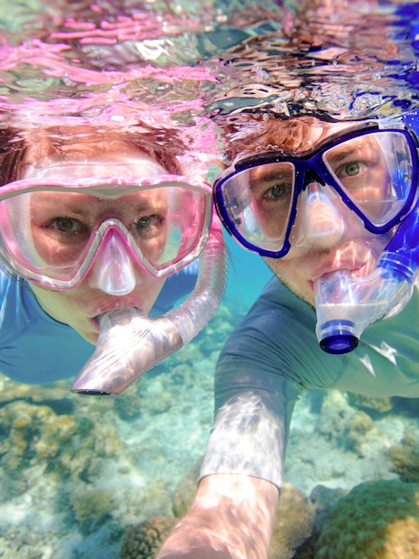 Couple snorkeling near coral reefs in clear waters, Oahu, Hawaii.