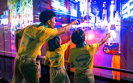 Visitors pointing at vibrant cityscape display at One World Observatory, New York.
