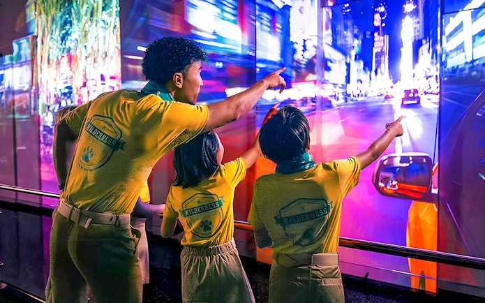 Visitors pointing at vibrant cityscape display at One World Observatory, New York.