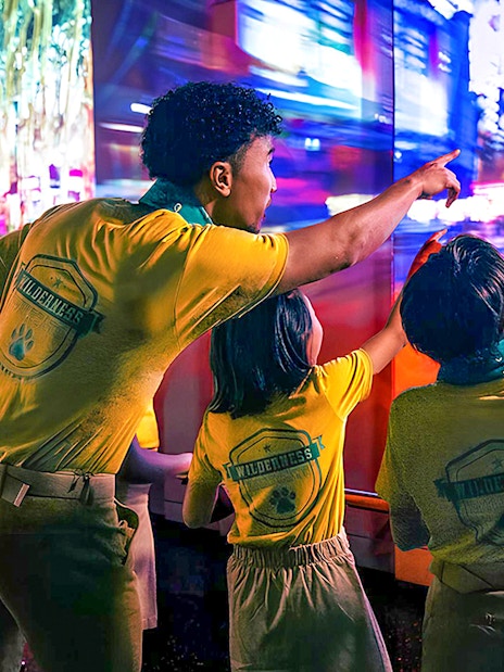 Visitors pointing at vibrant cityscape display at One World Observatory, New York.