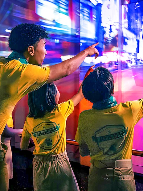 Visitors pointing at vibrant cityscape display at One World Observatory, New York.