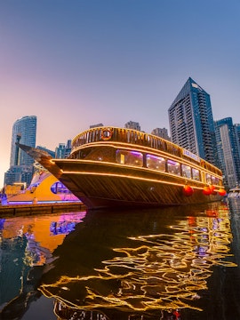 Alexandra Dhow Cruise illuminated at Dubai Marina during sunset.