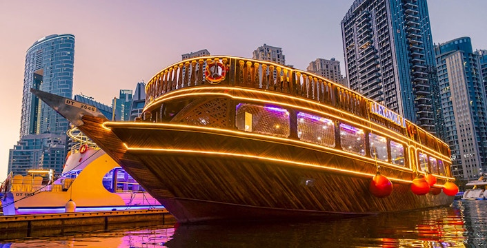 Alexandra Dhow Cruise illuminated at Dubai Marina during sunset.