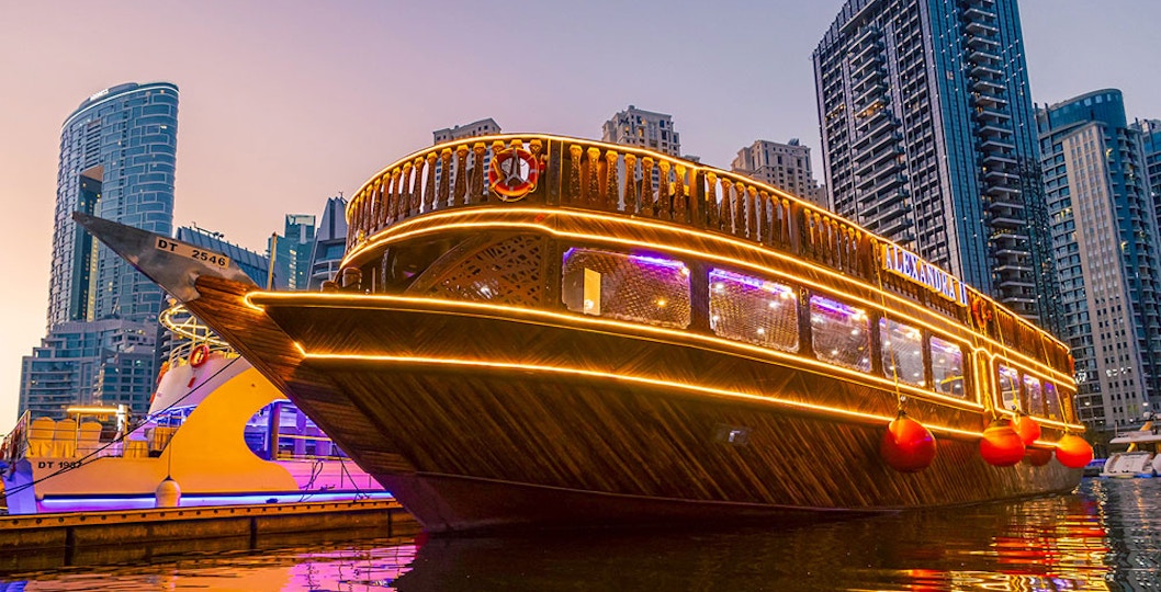 Alexandra Dhow Cruise illuminated at Dubai Marina during sunset.