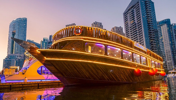 Alexandra Dhow Cruise illuminated at Dubai Marina during sunset.