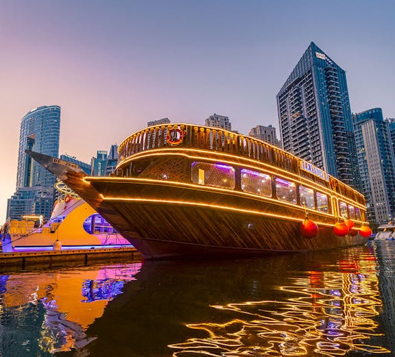 Alexandra Dhow Cruise illuminated at Dubai Marina during sunset.