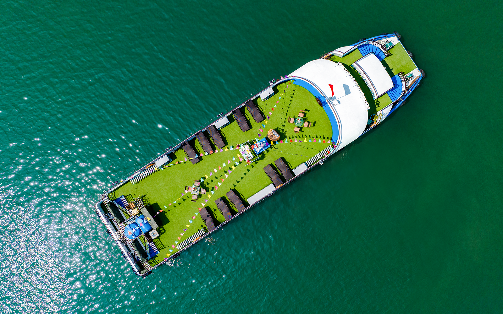 Aerial view of a cruise ship deck with sun loungers and seating, Ha Long Bay.