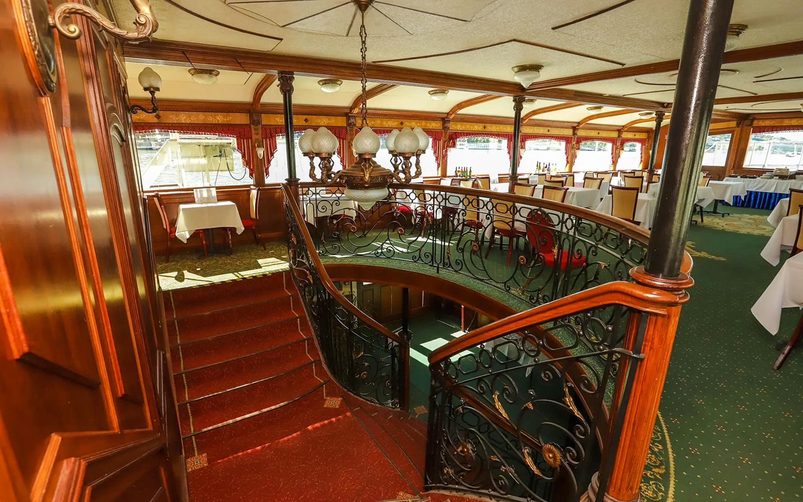 Interior of Sunshine Booze Cruise in Budapest with elegant dining area and ornate staircase.