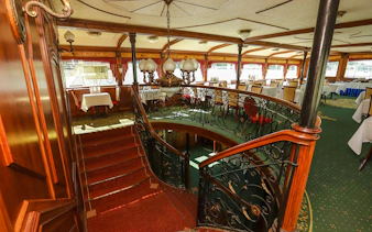 Interior of Sunshine Booze Cruise in Budapest with elegant dining area and ornate staircase.