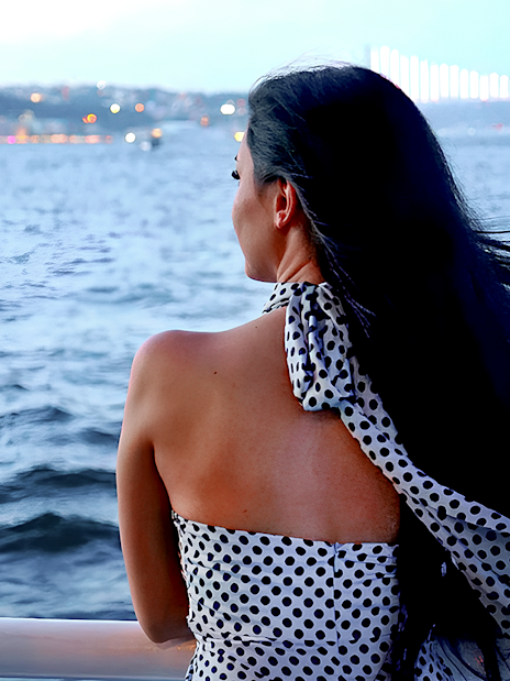 Person enjoying Bosphorus cruise with Istanbul skyline in the background.