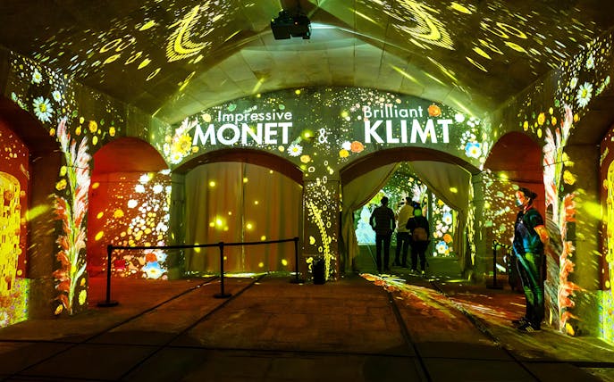 Immersive theater entrance with Monet and Klimt projections, featuring floral and light displays.