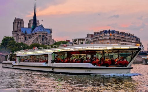 Dinner cruise on the Seine River with Notre-Dame Cathedral in the background, Paris.