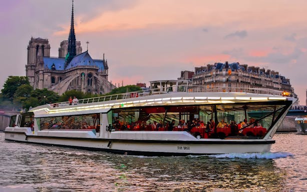 Dinner cruise on the Seine River with Notre-Dame Cathedral in the background, Paris.