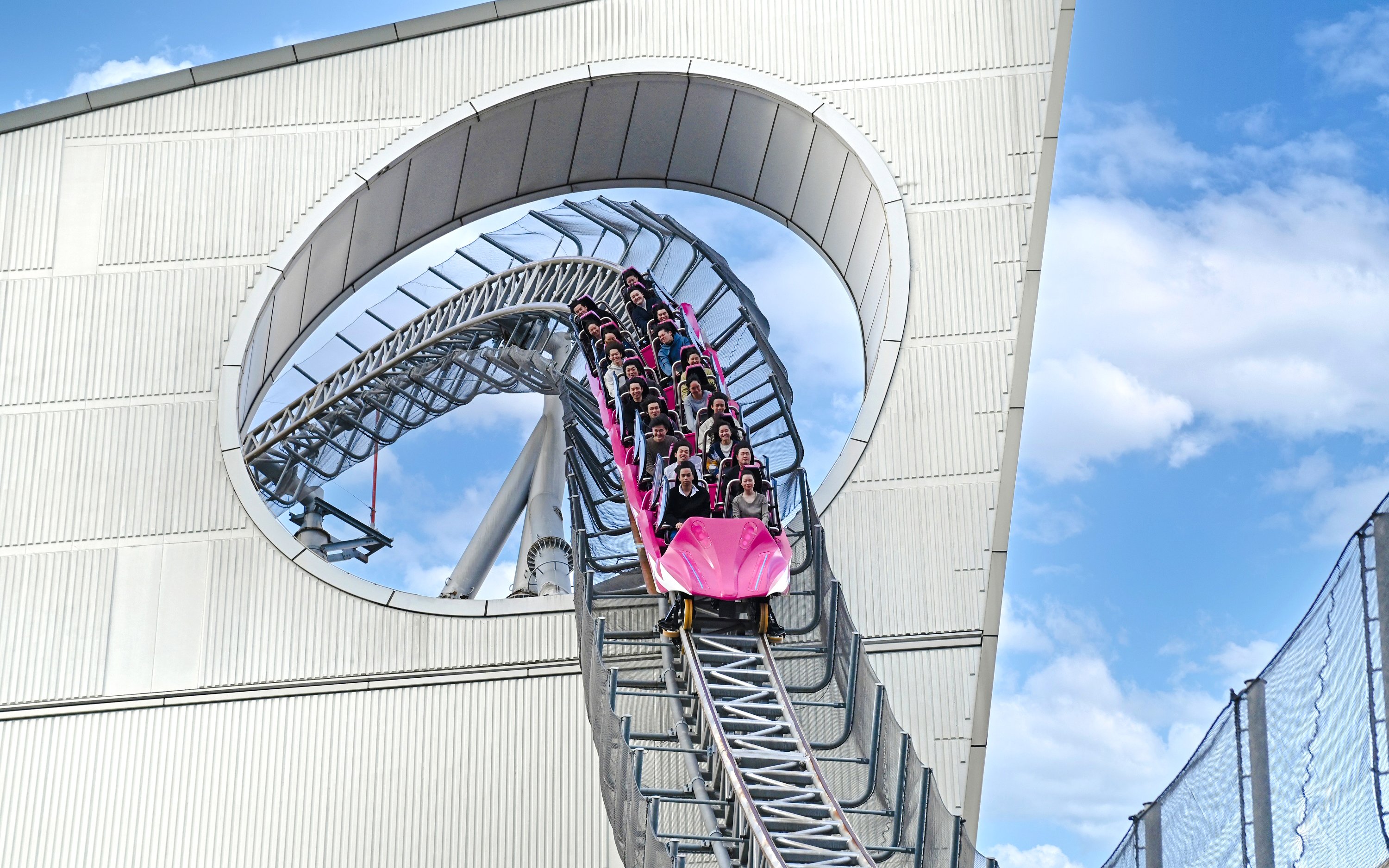 Roller coaster descending through a building loop at Tokyo Dome.