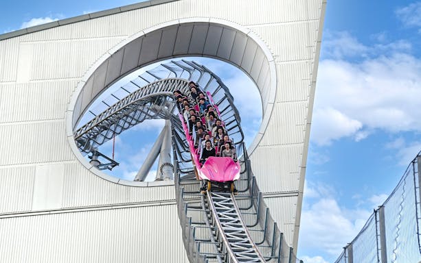 Roller coaster descending through a building loop at Tokyo Dome.