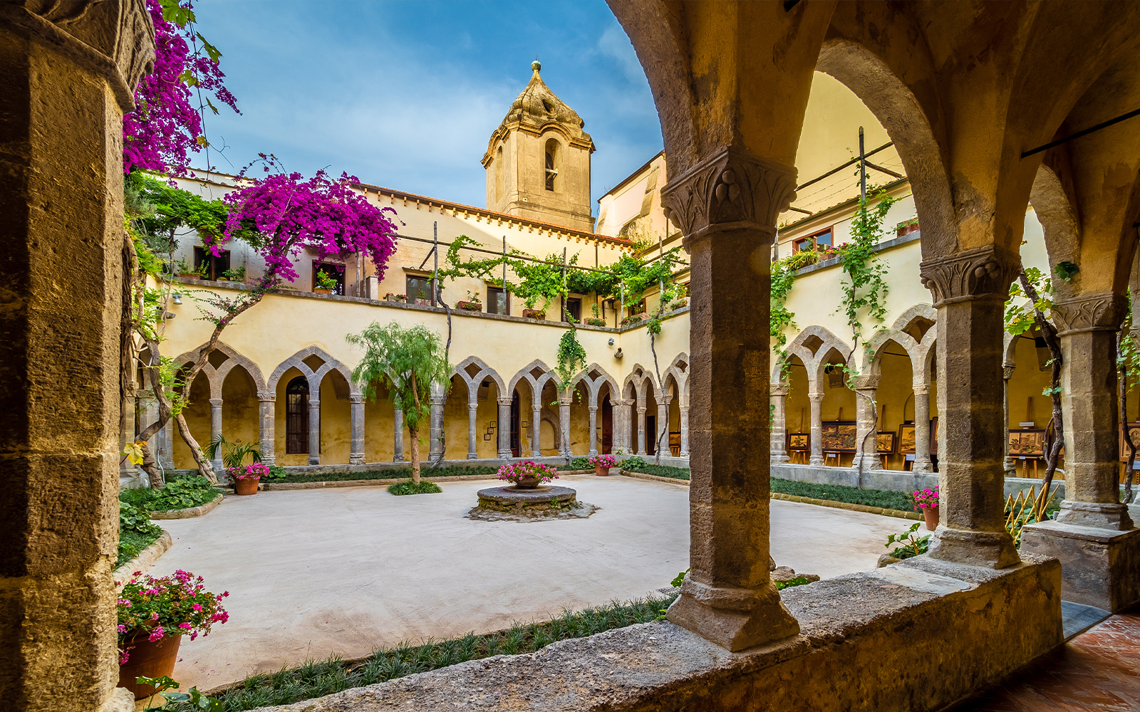 Chiostro San Francesco courtyard with arches and vibrant flowers in Sorrento.
