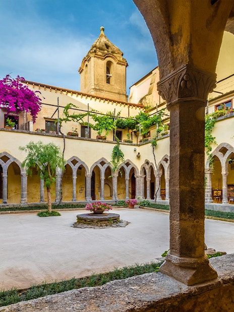 Chiostro San Francesco courtyard with arches and vibrant flowers in Sorrento.
