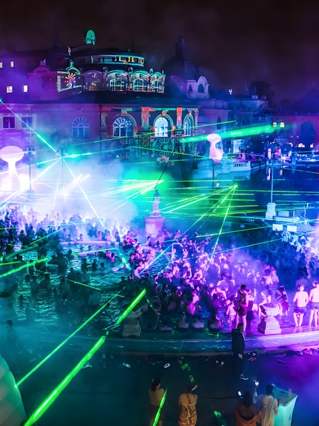 Crowd enjoying Sparty bath party with laser lights at Széchenyi Thermal Bath, Budapest.
