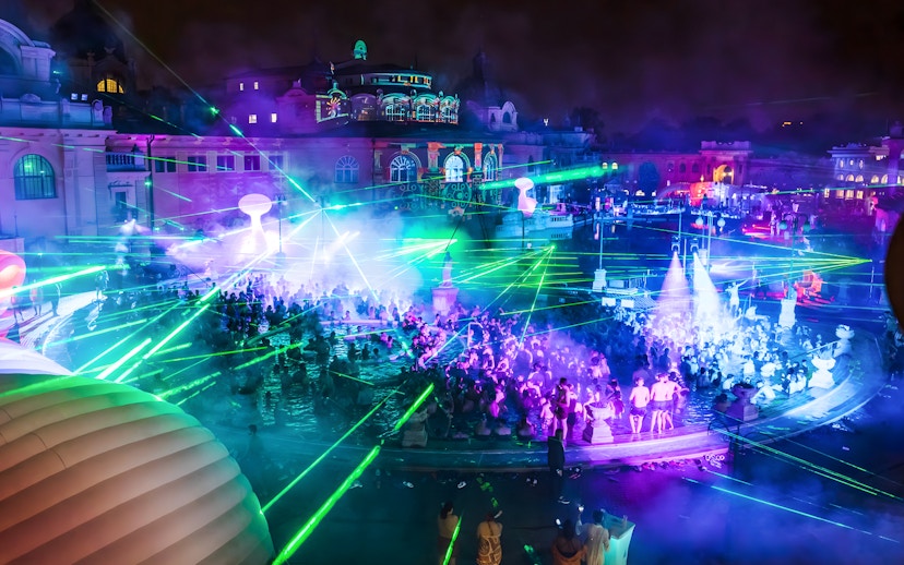 Crowd enjoying Sparty bath party with laser lights at Széchenyi Thermal Bath, Budapest.