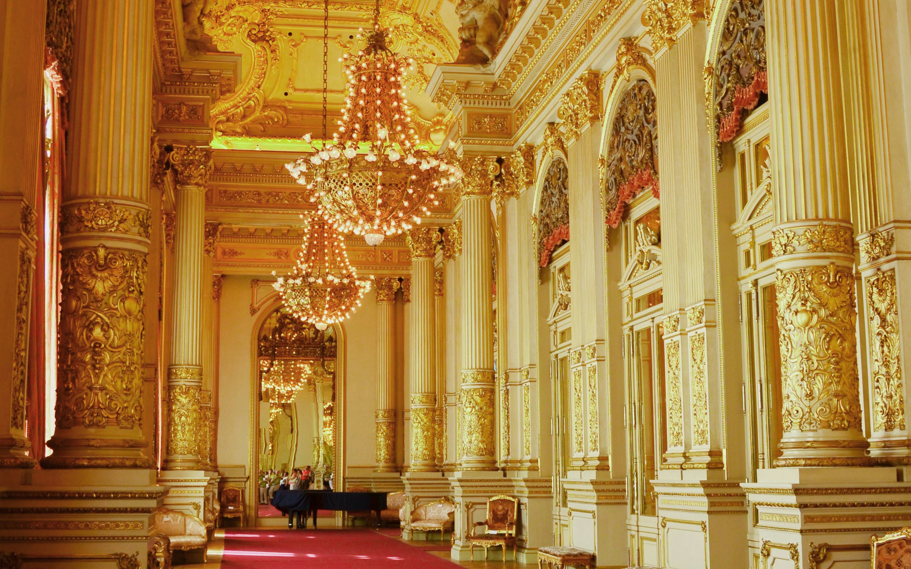Ornate interior of Teatro Colon with chandeliers and gilded columns.