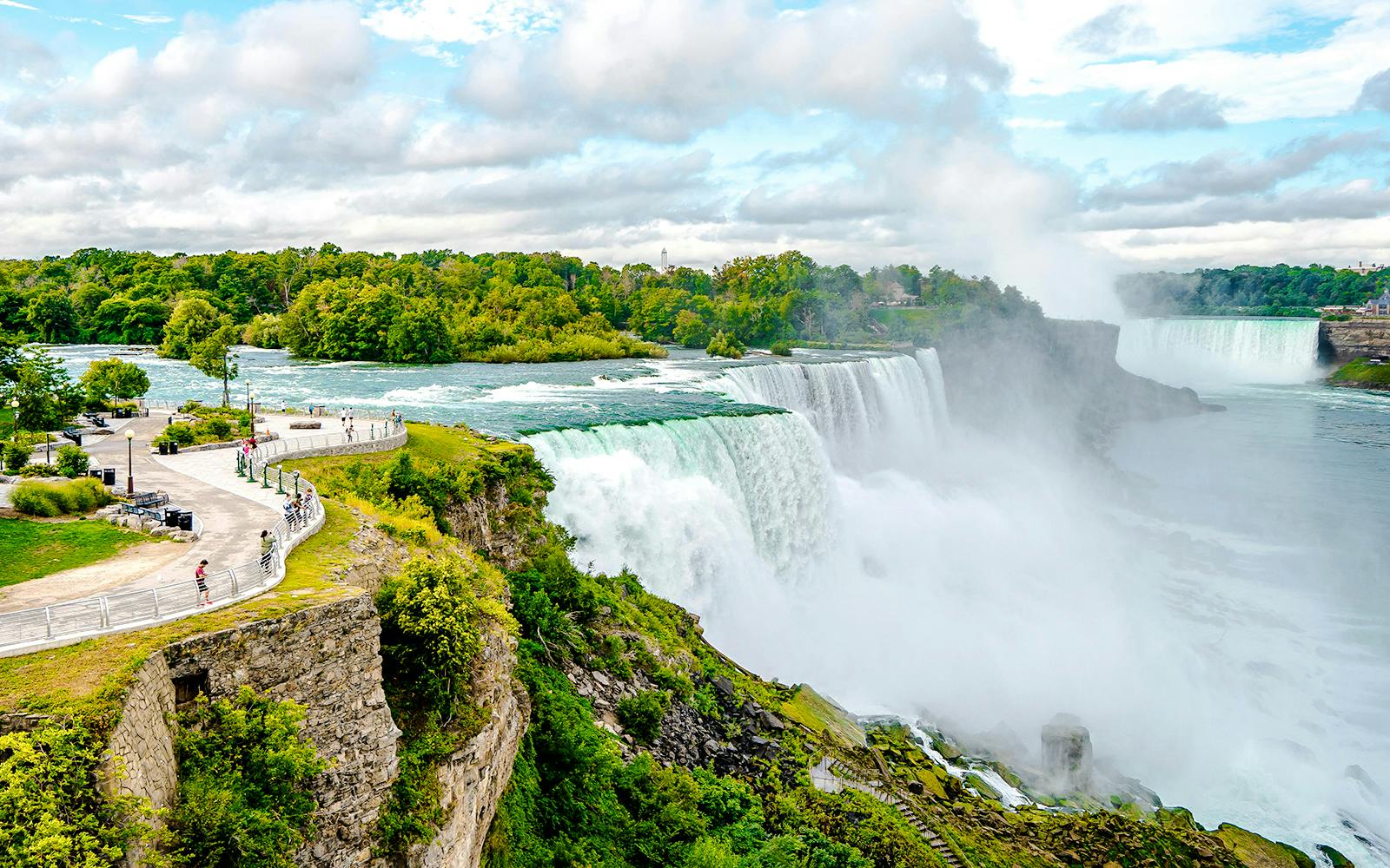 Niagara Falls USA with tourists on a viewing platform overlooking the cascading waterfalls.