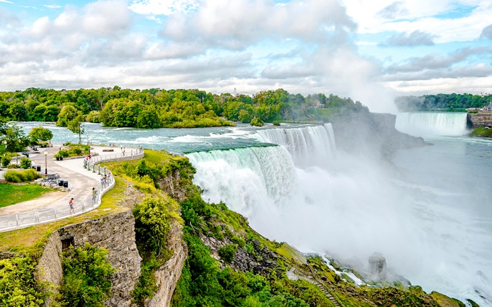 Niagara Falls USA with tourists on a viewing platform overlooking the cascading waterfalls.