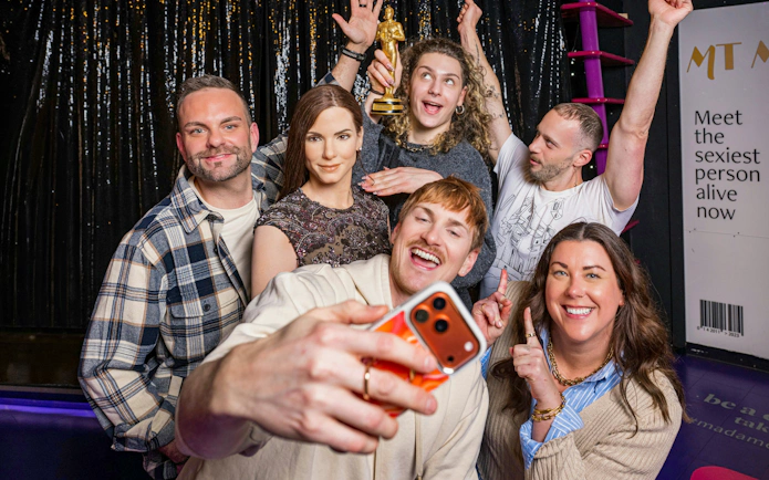 Group taking selfie with wax figure at Madame Tussauds Vienna.