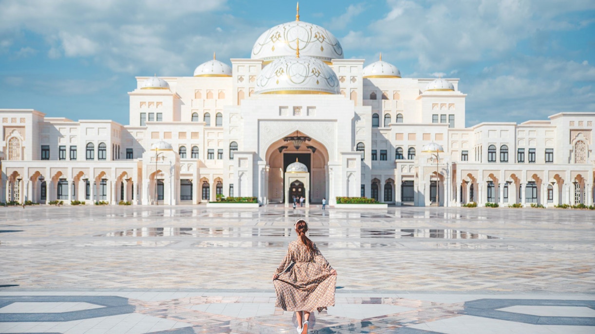 Woman walking towards Qasr Al Watan in Abu Dhabi, showcasing the palace's grand architecture.