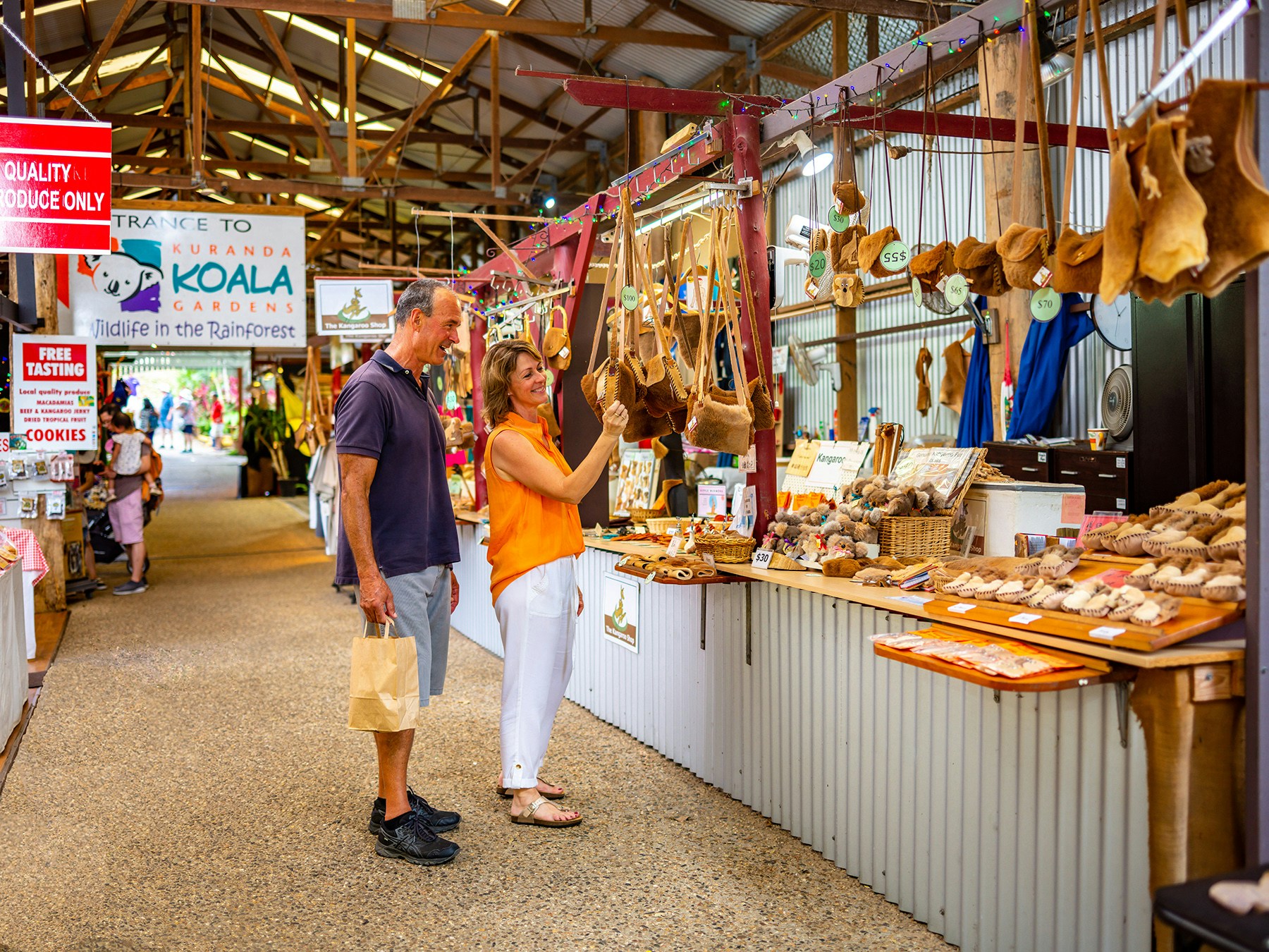Kuranda market stall with local crafts and visitors browsing, part of Scenic Train and Skyrail Kuranda Tour.