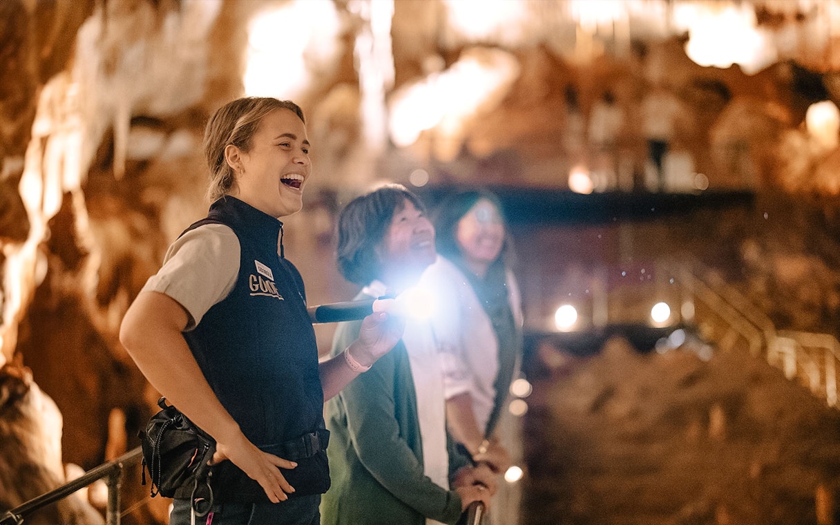 Guide leading a tour in Jewel Cave, Margaret River, with visitors observing stalactites.
