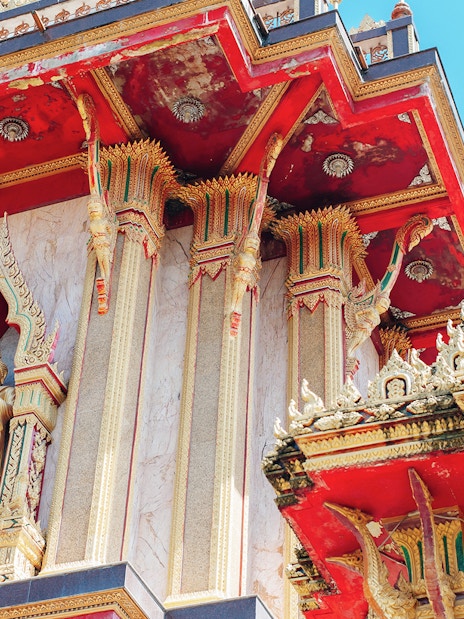 Wat Chalong temple architecture in Phuket, featuring ornate red and gold details.