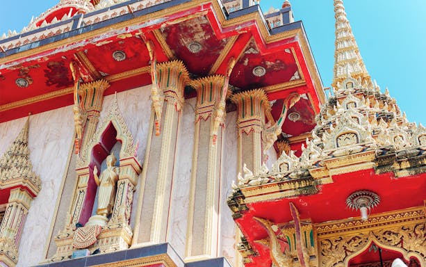 Wat Chalong temple architecture in Phuket, featuring ornate red and gold details.