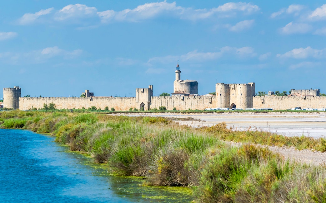 Towers and ramparts of Aigues-Mortes with surrounding landscape and waterway.