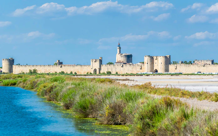 Towers and ramparts of Aigues-Mortes with surrounding landscape and waterway.