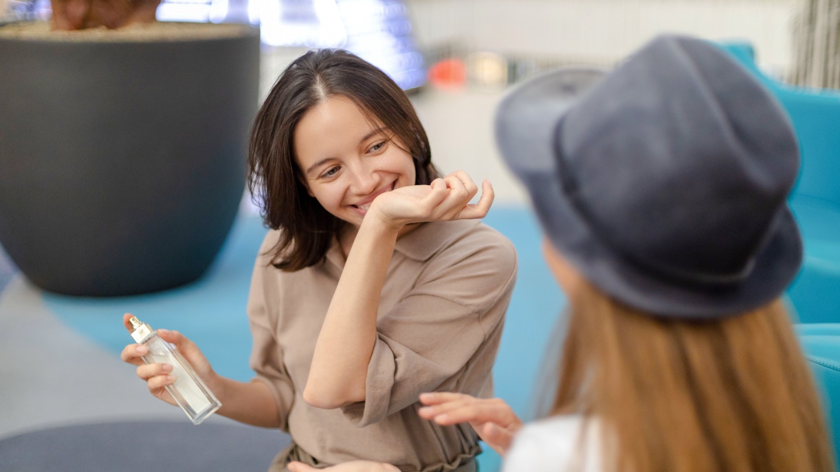 Young woman enjoying perfume scent on her hand in a shopping mall.