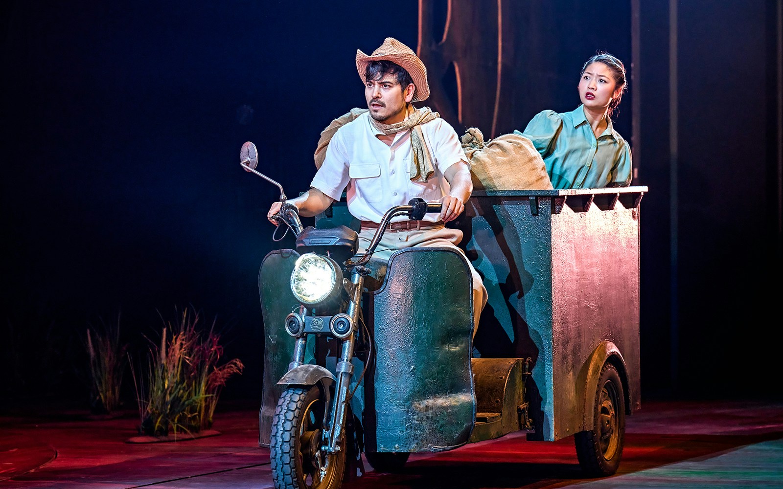 Man and woman on stage in a My Neighbour Totoro performance, riding a motorized cart.
