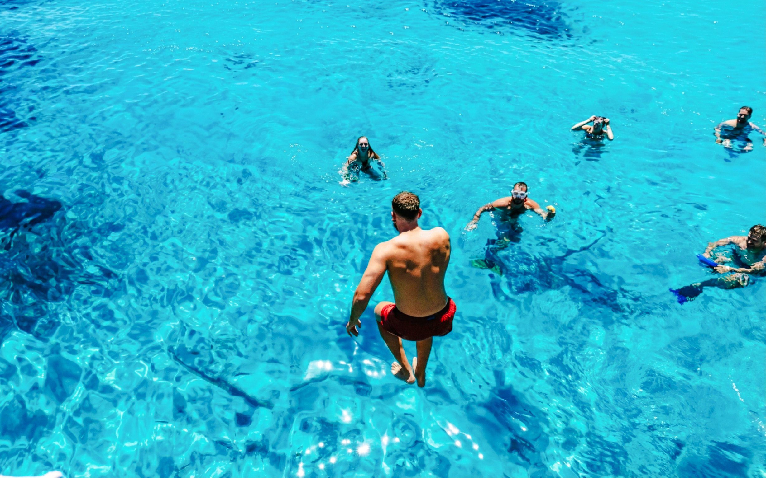 People swimming in clear blue waters during a motorboat tour of the La Maddalena Archipelago.