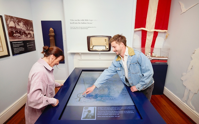 Two people engage with an interactive map display at Cape Naturaliste Lighthouse museum.
