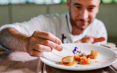 Chef garnishing dish on Vivid Sydney dinner cruise.