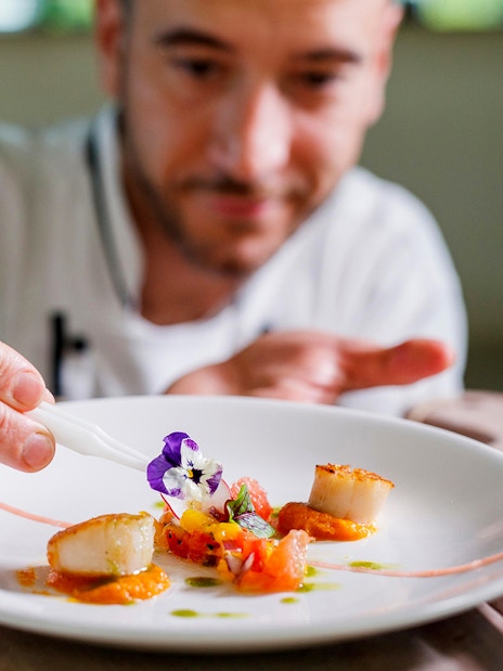 Chef garnishing dish on Vivid Sydney dinner cruise.
