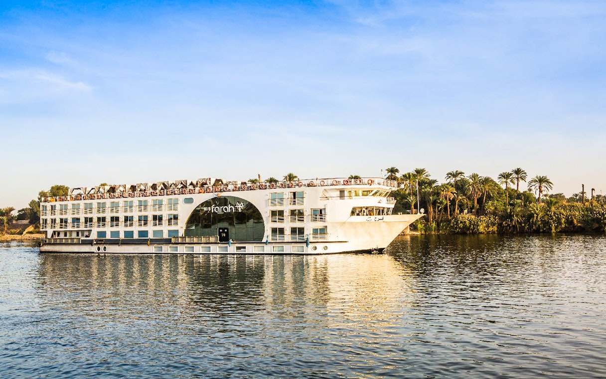 Cruise ship on the Nile River with palm trees in the background during a 4-day Nile cruise.