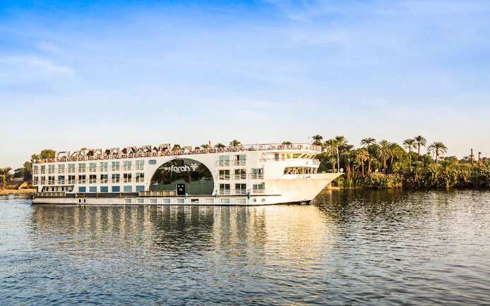 Cruise ship on the Nile River with palm trees in the background during a 4-day Nile cruise.