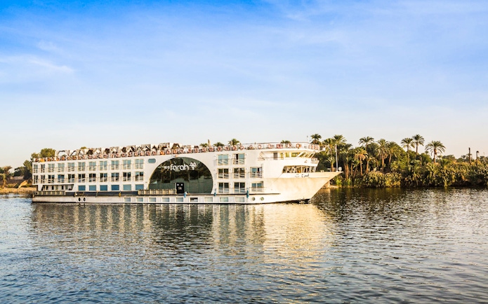 Cruise ship on the Nile River with palm trees in the background during a 4-day Nile cruise.