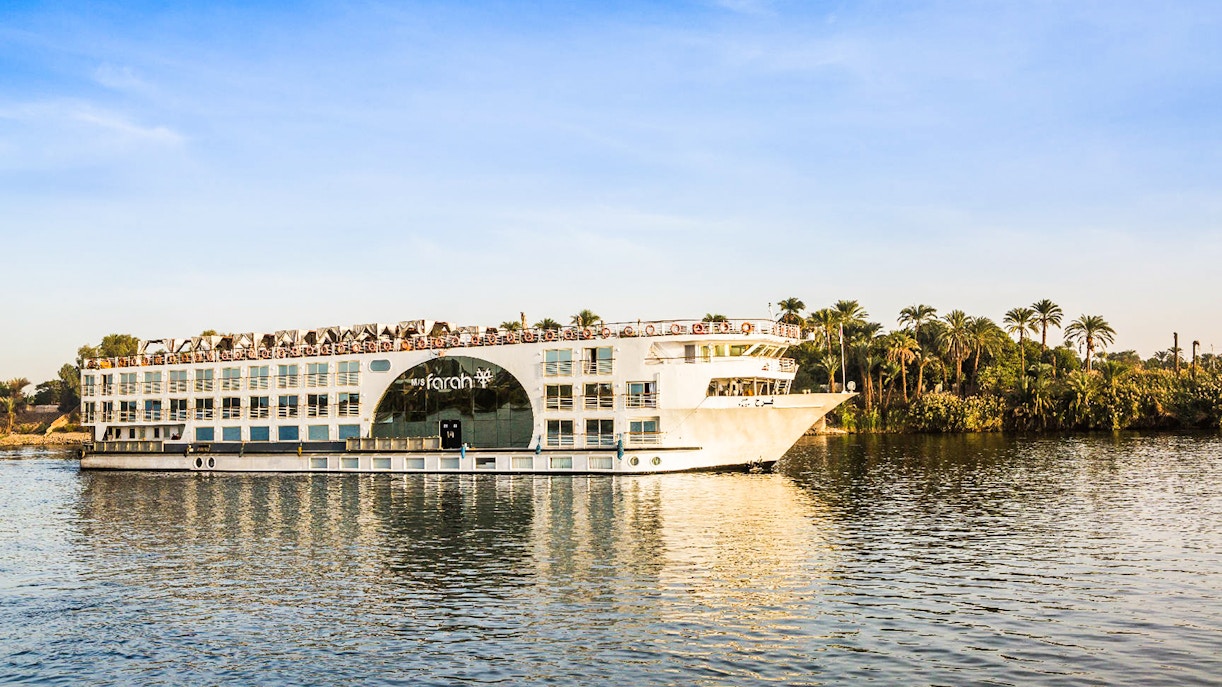Cruise ship on the Nile River with palm trees in the background during a 4-day Nile cruise.