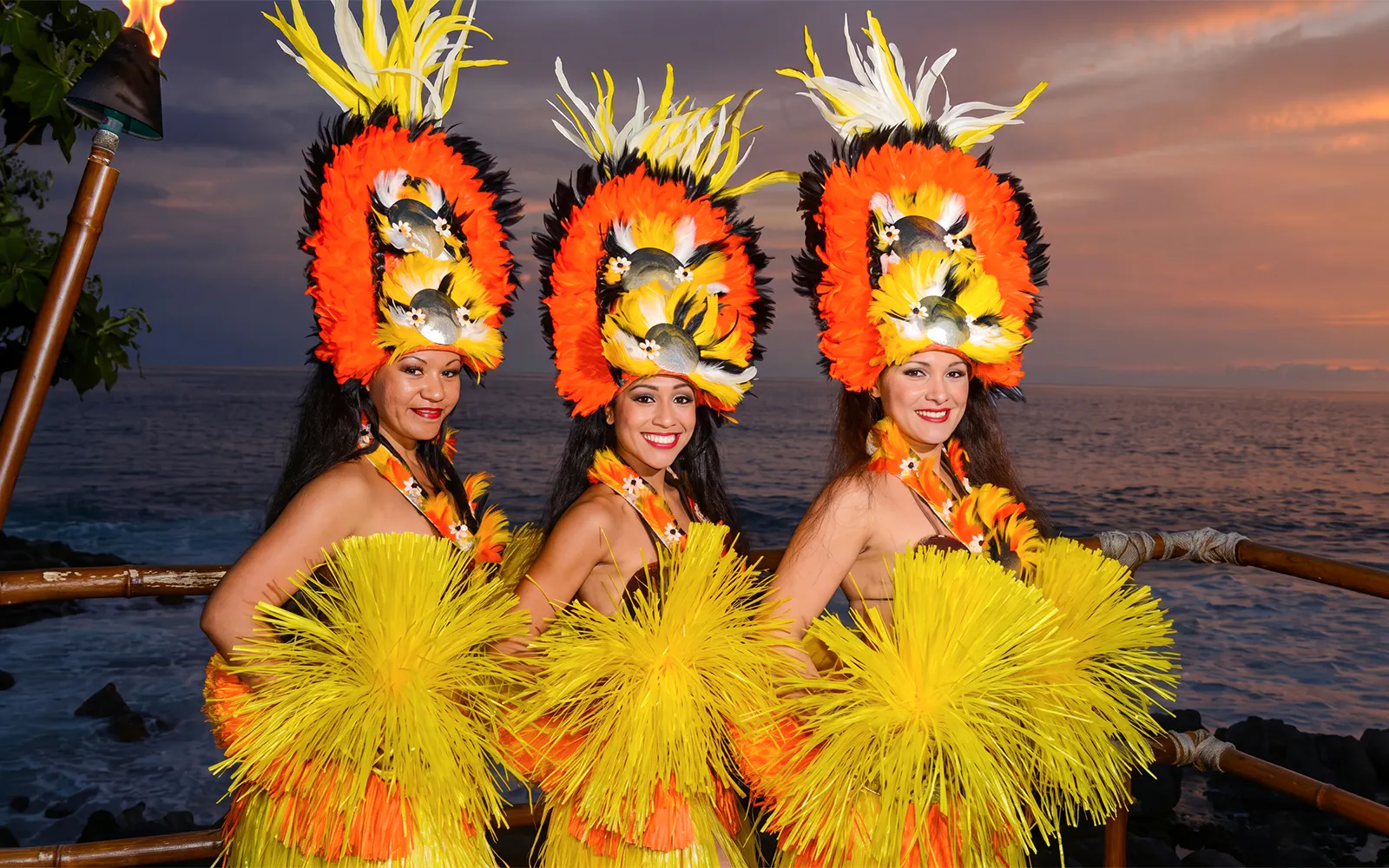 Performers in traditional attire at Voyagers of the Pacific Luau, Hawaii, with ocean backdrop.