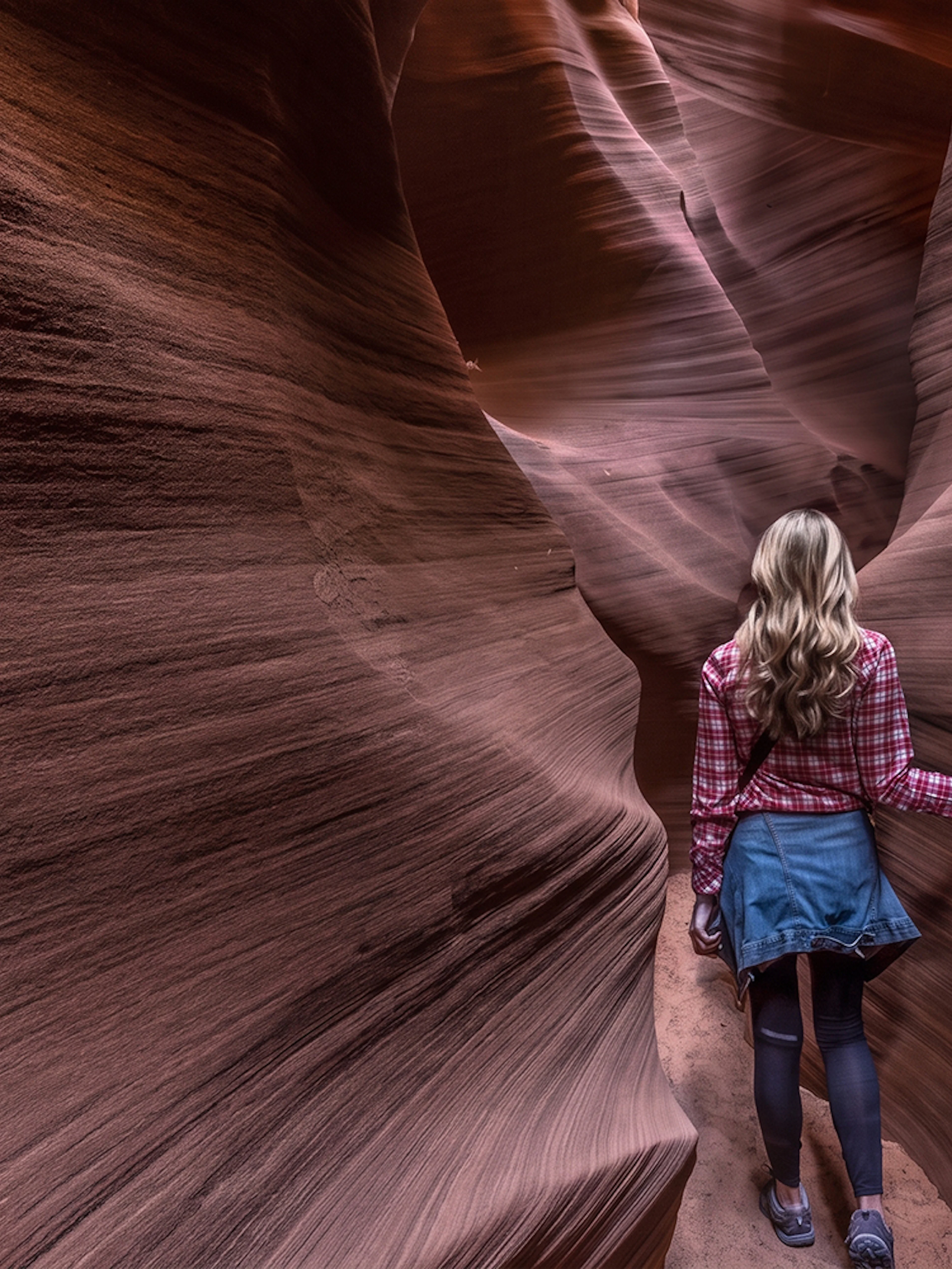 Visitor exploring narrow sandstone passage in Secret Antelope Canyon tour.