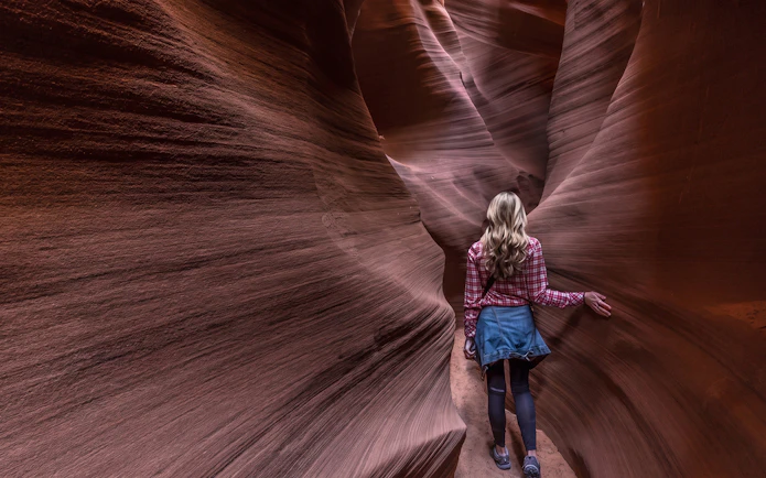 Visitor exploring narrow sandstone passage in Secret Antelope Canyon tour.